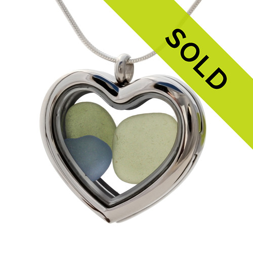 Green and Carolina Blue sea glass heart combined a large silver heart in this sea glass locket necklace.