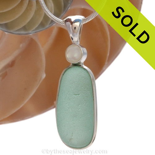 Along piece of top quality aqua English sea glass pendant set with a round mother of pearl in a tube bezel setting. Sorry this piece of Sea Glass Jewelry has been SOLD!