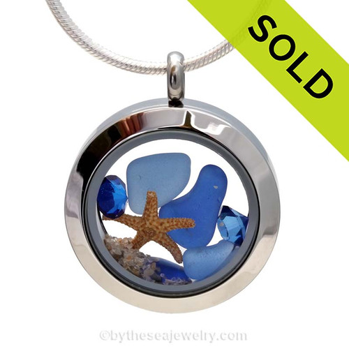 Genuine sea glass in cobalt blue and the lighter Carolina Blue, a real baby starfish in this mini sea glass locket necklace. Sapphire Gems bring in a bit of beachy bling to the piece.
SOLD, sorry this sea glass jewelry piece is no longer available.