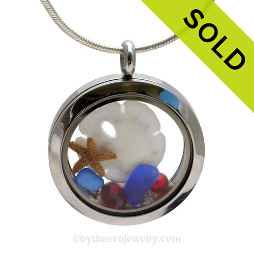 A beautiful sliver of natural blue sea glass combined in a stainless steel locket necklace a real starfish and Baby Sandollar . Vivid Ruby Gems complete the beachy look.
This a great gift, specially for those with a September or July Birthday.
SOLD - Sorry this Sea Glass Locket is NO LONGER AVAILABLE!