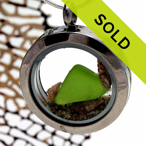 Beautiful small piece of vivid lime green sea glass combined with a small shells and beach sand in a stainless steel locket.
Sorry this locket has been sold!