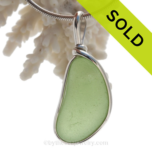 A Cool bean shaped Piece of Yellowy Seawater Green beach found glass set in our Original Wire Bezel© pendant setting.