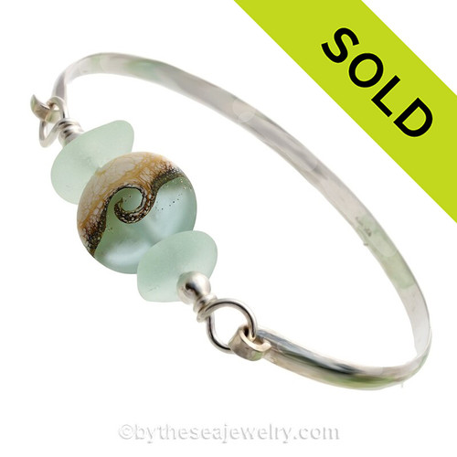 Genuine Sea Green Perfect Sea Glass Bangle set with a handmade lamp work glass wave bead with sterling end beads on a Solid Sterling half round Bangle Bracelet.
This is a medium bangle at 7.75 inches.