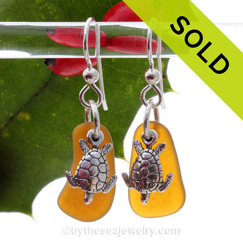 Natural amber brown sea glass pieces are set with solid sterling sea turtle charms and are presented on sterling silver fishook earrings.