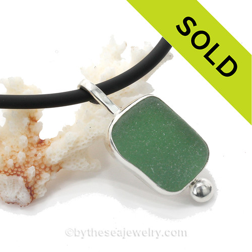 A stunning large and perfect piece of beach found green sea glass set in fine silver on a thick neoprene cord