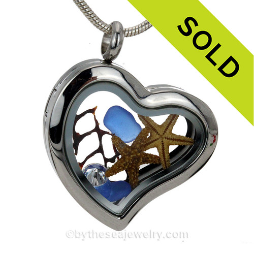 A stainless steel heat locket with blue sea glass, two starfish and a diamond.