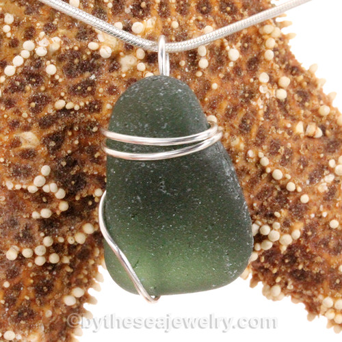 A nice piece of genuine and very thick sea glass in dark green and a simple secure  wire wrapped sterling setting.