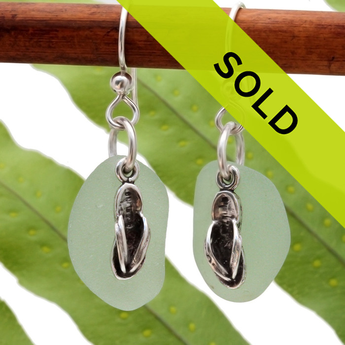 Natural seafoam green sea glass pieces are set with solid sterling flip flop charms and are presented on sterling silver fishhook earrings.