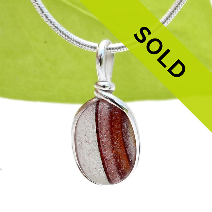 A beautiful mixture of vivid red and gold fused on a pure white sea glass piece. This piece is set in our Original Wire Bezel© setting and leaves this amazing natural sea glass piece UNALTERED from the way it was found on the beach!
Sorry this sea glass jewelry has sold!