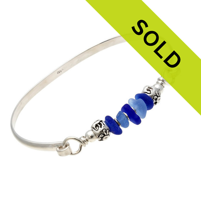 Five pieces of beach found sea glass in light and dark blue on this solid sterling silver half round sea glass bangle bracelet. Finished with solid sterling sea life beads to remind you more of the beach.
Sorry this sea glass bracelet is no longer for sale.