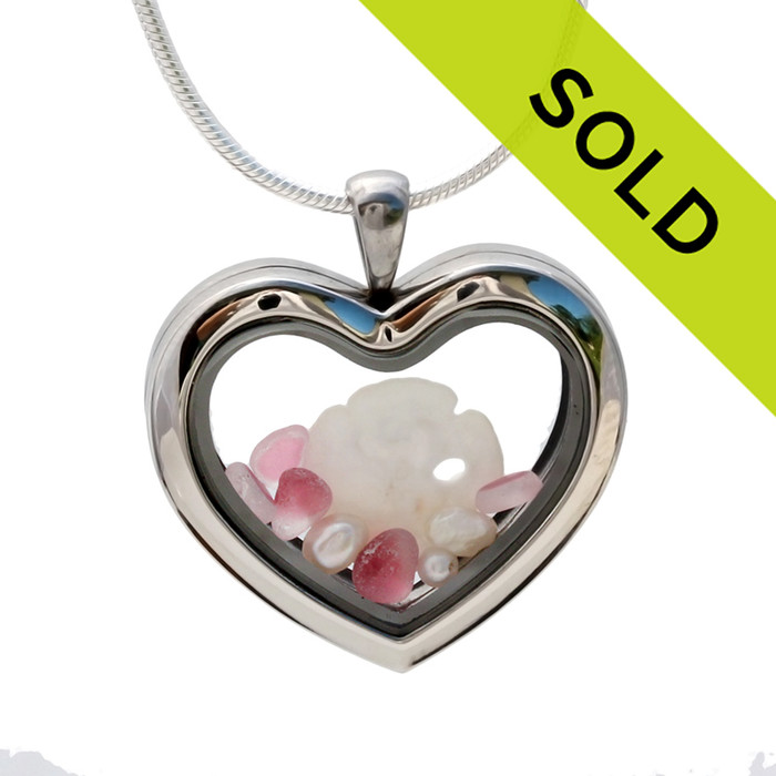 Small flashed pink sea glass pieces combined with a sandollar and pearls in a feminine heart shaped locket.
Sorry this sea glass locket has been sold!