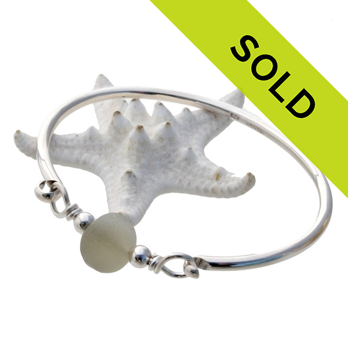 A thick piece of off white sea glass combined with sterling beads on a solid sterling bangle bracelet.
Sorry this sea glass jewelry piece has been sold!