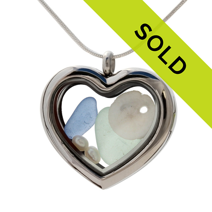 Our new heart lockets make this green and light blue sea glass really shine! A tiny sandollar and fresh water pearls completes the beachy look!
Genuine beach found glass.