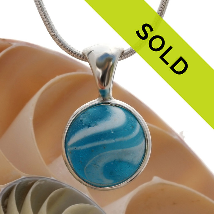 A stunning electric aqua sea glass marble mixed with white opaque glass in our Deluxe Wire Bezel© pendant setting.

Sorry this sea glass necklace pendant has been sold!