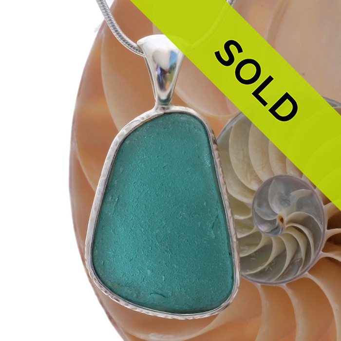 A really neat almost perfectly flat but thick piece of VIVID Teal sea glass set in our Deluxe Wire Bezel© necklace pendant setting.
Sorry this sea glass necklace pendant is no longer available.