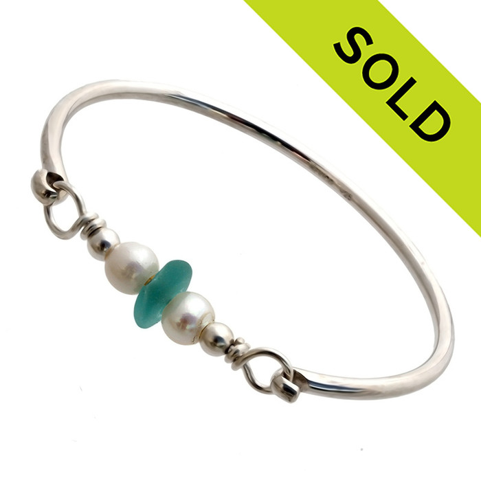 A vivid tropical aqua sea glass piece from Hawaii are combined with a two genuine fresh water pearls on a solid sterling bangle round bracelet.
Sorry this Sea Glass Bracelet has been SOLD!