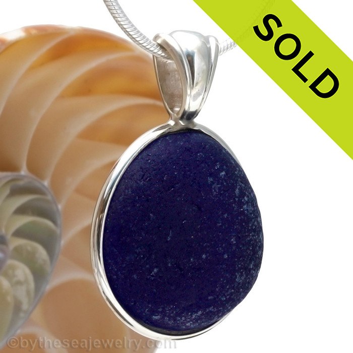 A stunning thick piece of genuine UNALTERED sea glass in an elegant setting.A perfect and LARGE piece of vivid Midnight Blue sea glass from the UK in our In Deluxe Sterling Wire Bezel© Setting that leaves the glass just the way it was found on the beach. 
Sorry this one of a kind sea glass jewelry piece has been sold!