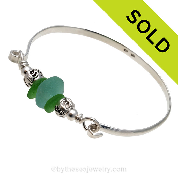 Two pieces of beach found sea glass in a vivid green with a handmade aqua center  bead  on this solid sterling silver half round sea glass bangle bracelet. 
SOLD - Sorry This Sea Glass Bracelet Is NO LONGER AVAILABLE!