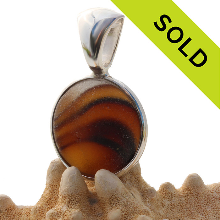 A True Sea Glass Pendant set in our Deluxe Wire Bezel© settings. A great piece mixed amber and clear that seems to come alive inside this amazing sea glass piece.