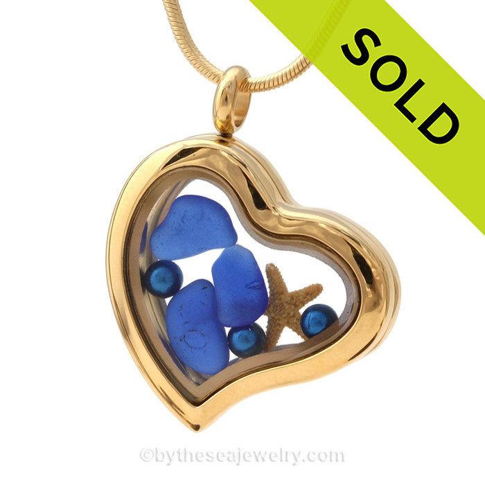 A goldtone stainless steel locket with beach found Cobalt Blue Sea Glass, a real baby starfish , finished with blue dyed pearls.