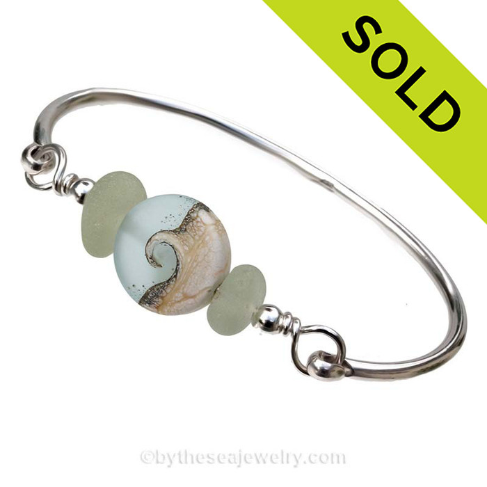 Genuine Seaofam Green Sea Glass Bangle Bracelet set with a handmade lampwork glass wave bead in sof aqua with sterling end beads on a solid sterling full round premium bangle bracelet.
SOLD - Sorry this Sea Glass Bangle Bracelet is NO LONGER AVAILABLE!