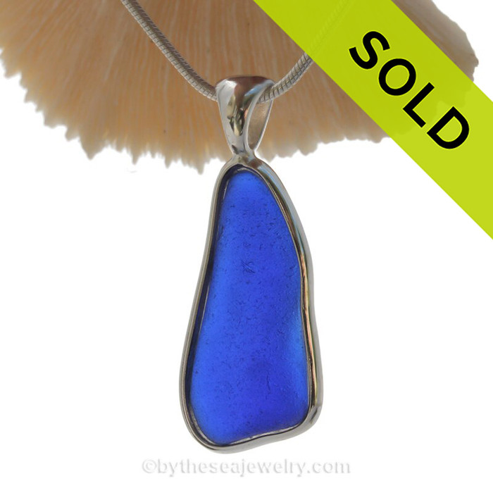 A long slice of Lovely and Tactile Cobalt Blue Beach Found Sea Glass In Solid Sterling Silver Deluxe Wire Bezel© Necklace Pendant. This Setting that leaves the sea glass piece just the way it was found on the beach and combines our original deluxe wire setting taken to the to the next level by incorporating a Solid Sterling cast bail.