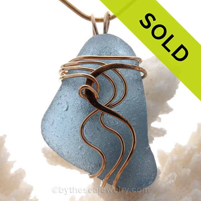 A perfect beautiful warm gray blue Genuine Sea Glass piece in our signature Squiggles setting in gold.