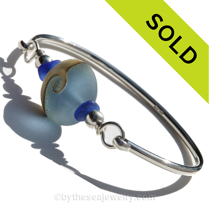 Cobalt Blue Genuine Sea Glass Bangle Bracelet set with a handmade lampwork glass Wave bead set with Sterling Details on a Solid Sterling Round Bangle Bracelet.
This is a medium bangle at 7.5 inches.
SOLD - Sorry this Sea Glass Jewelry selection is NO LONGER AVAILABLE!