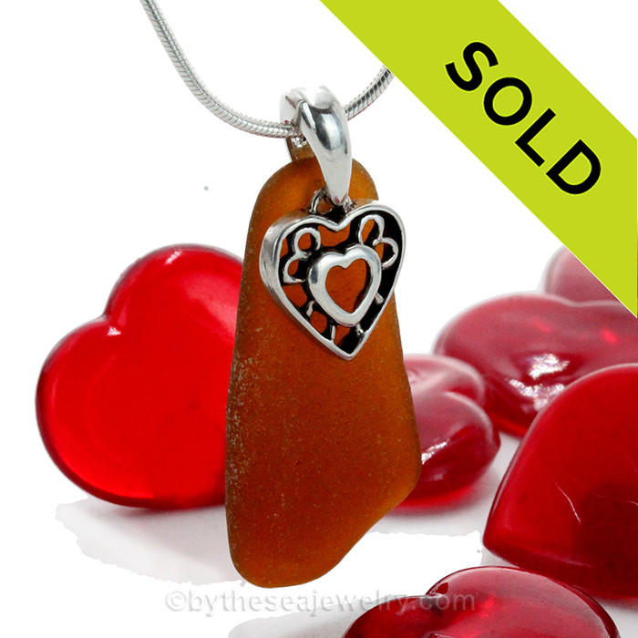 A long and  lovely perfect amber honey brown genuine sea glass with a solid sterling bail and detailed heart in heart charm.