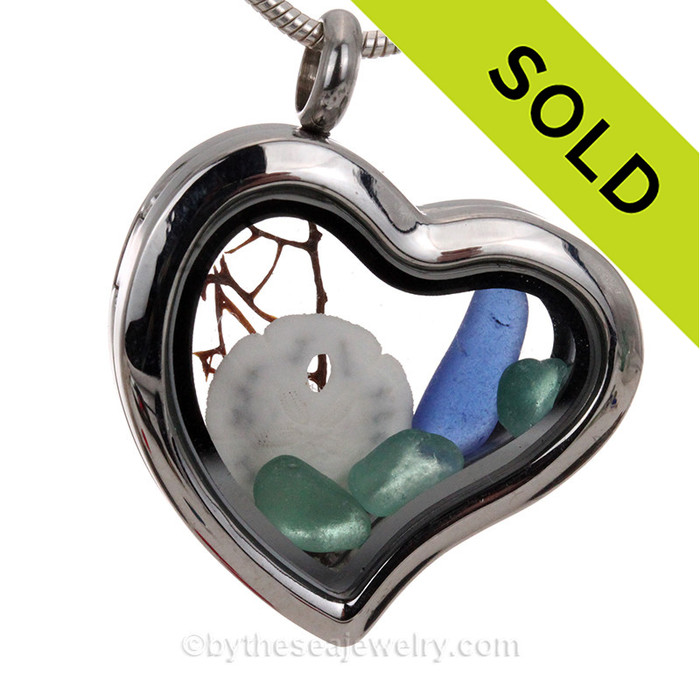 An  Aqua and Blue  sea glass piece in combined with a real sand dollar combined a heart locket in this sea glass locket necklace.