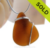 A nice piece of genuine sea glass in amber brown and a simple secure  wire wrapped sterling setting.