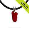 Rare Mini Ruby Red sea glass pendant on a black neoprene cord.