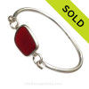 A PERFECT piece of deep Vivid Ruby Red Sea Glass Bangle Bracelet set in our Deluxe Wire Bezel© Sterling Silver Setting.
This setting leaves the sea glass piece TOTALLY UNALTERED from the way it was found on the beach. 