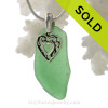 Green genuine sea glass with a solid sterling bail and detailed heart in hearts charm.