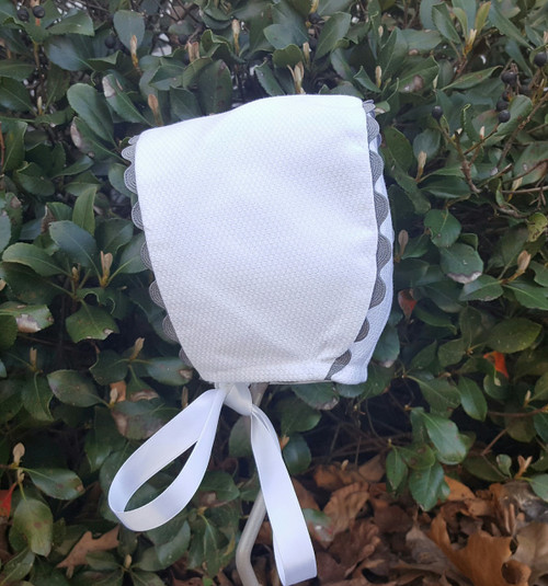 White pique bonnet with grey trim.