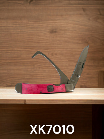 Twisted X pink hoof pick and serrated folding knife tool for horse care and ranch use on wooden background