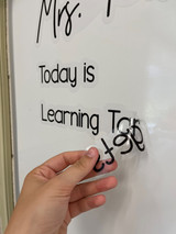 Hand applying personalized Today Is and Learning Target clings to a whiteboard