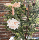 Engaged ornament with a blush ribbon hanging on a tree