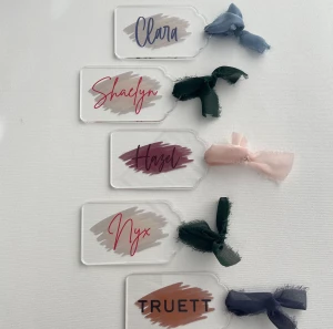 Personalized acrylic name tags with brushstroke backgrounds and ribbons