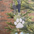 White paw print ornament with a pet name and a dark blue ribbon