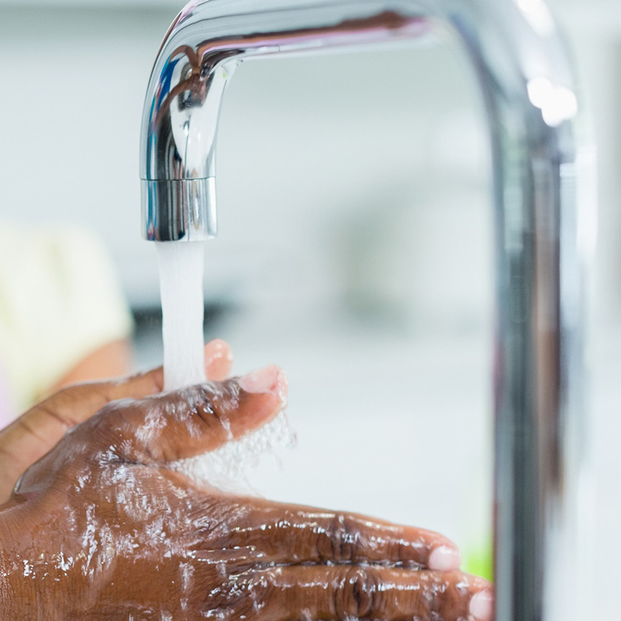 Dual Threaded Bubble Faucet Aerator installed on a kitchen faucet washing person's hand