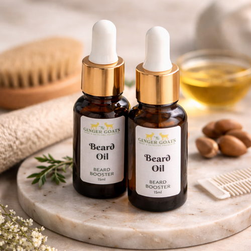 Two amber glass beard oil bottles with gold droppers on a marble tray, styled with a wooden beard brush, comb, and natural oils in a bathroom setting.