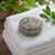 Tea Tree and Nettle shampoo bar resting on folded white fluffy towels in a soft, natural bathroom setting with gentle lighting and greenery in the background.