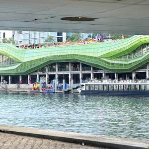 Viewed from the opposite bank, the bold architecture of La Cité de la Mode et du Design stretches along the Seine, combining fashion, design, nightlife, and cultural spaces under one remarkable riverside complex. During warmer months, visitors gather on the rooftop terraces and along the quays from afternoon until late into the evening.