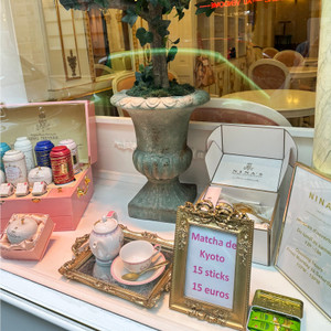 Tea tins, porcelain, and sweet treats fill the window display at Nina's Marie-Antoinette, where signature blends are inspired by the flavours said to have been favoured by Marie-Antoinette herself, including rose, apple, and delicate floral notes.