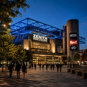 A striking, modern venue set in the heart of Paris' La Villette district. The exterior showcases its iconic futuristic architecture, with sleek lines and glowing LED lights that change color. Inside, the expansive concert hall features a high-tech sound system and dramatic lighting, creating an immersive experience for every concertgoer. Fans are seen enjoying live performances in a buzzing atmosphere, with world-class artists lighting up the stage.