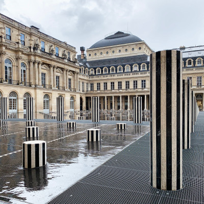 Palais Royal after the rain. The black-and-white columns of Daniel Buren reflect across the wet courtyard, creating one of the most photographed and recognizable scenes in Paris.