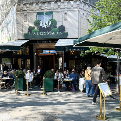 A relaxed street-side view of Les Deux Magots, where classic Parisian café culture unfolds beneath its iconic awnings.
