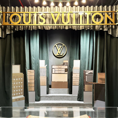 A theatrical entrance introduces the Louis Vuitton universe, blending heritage, craftsmanship, and modern display.