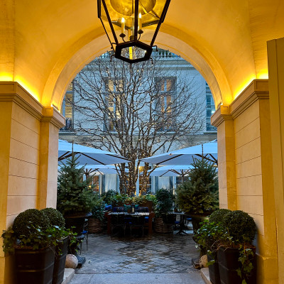 As evening falls, the courtyard shifts into a softer rhythm — warm light, quieter tables, a different kind of Paris.
